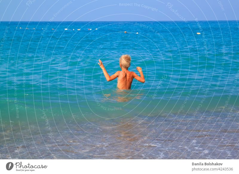 boy enters gently with his hands up into the cold summer sea water kid lifestyle jump splash happy kids fun throw turkey child people vacation beach bright