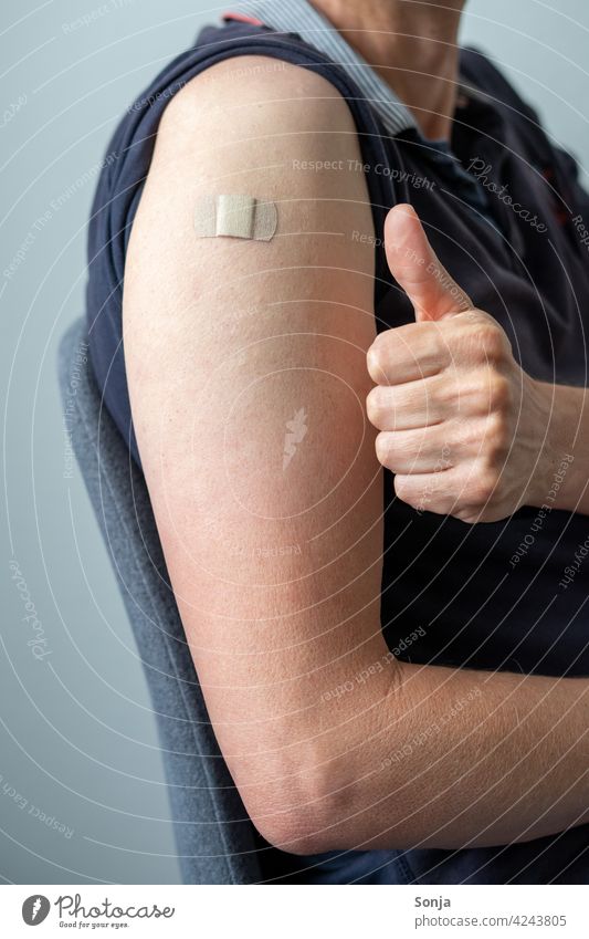Man with a sticking plaster on his arm and thumbs up Immunization Adhesive plaster coronavirus prevention Healthy Virus pandemic Illness medicine flu Thumbs up