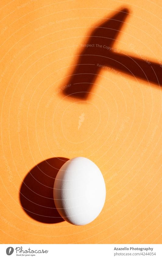 Minimal concept with an egg under the harsh light and a hammer shadow on an orange background healthy wallpaper life black destruction tool silhouette device