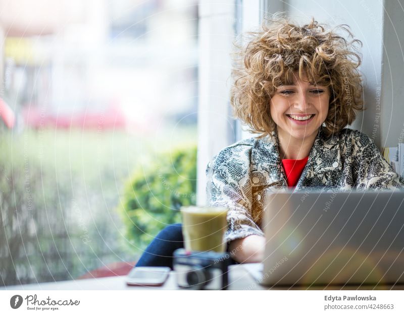 Young woman working on her laptop in cafe enjoying lifestyle young adult people one person casual caucasian positive carefree happy smile smiling female