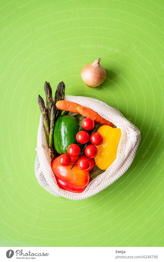 Fresh raw vegetables in a reusable shopping bag on a green background. Top view. Vegetable Raw String bag Reusable Healthy Organic Vegetarian diet naturally