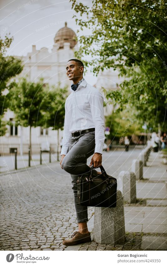 Young African American businessman waitng a taxi on a street building city young people travel traveler modern station traveller suitcase manager urban black