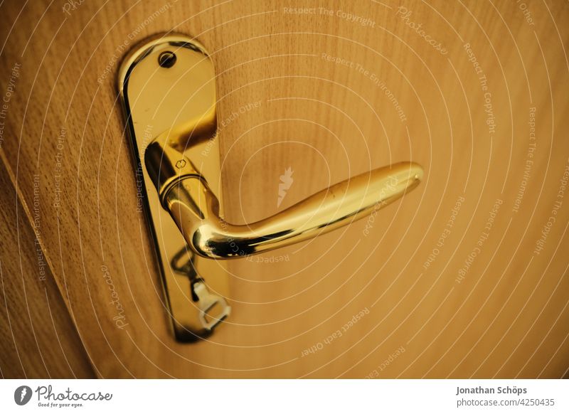 golden door handle with key on wooden door in apartment locked Close-up Front door Wooden door Door handle Entrance Closed Deserted Lock Structures and shapes