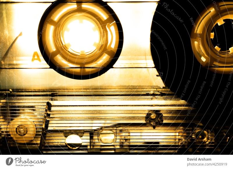 Abstract Closeup of See Through Cassette Tape with Dramatic Sepia Toned Lighting cassette tape reels see through clear music media audio analog hipster vintage
