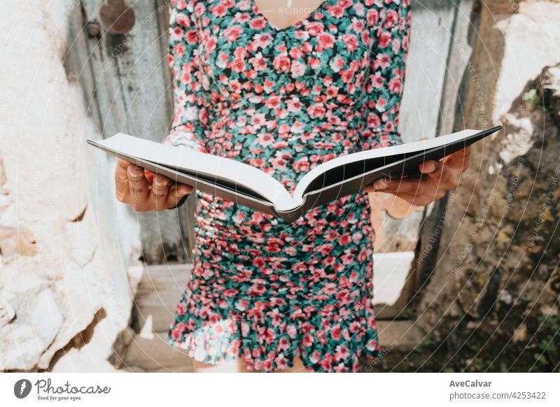 Close image of a woman in a dress grabbing a book while reading it with copy space education person library literature open page school student paper cover hold