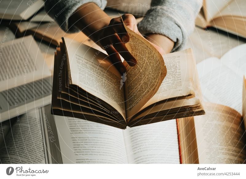 Close up of a pair of black hands reading an old book with copy space over a bunch of books education person library literature open page school student paper