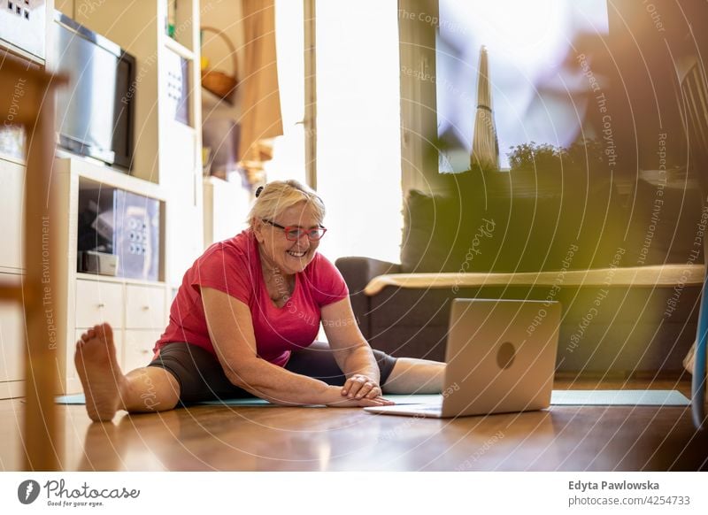 Senior woman exercising at home eyeglasses wrinkles natural real people casual day lifestyle grandmother pensioner aged leisure retirement retired one person