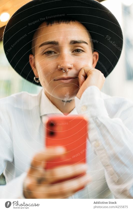 Pensive tomboy with smartphone in cafe woman identity queer weird alternative think style female eccentric transgender gadget neutral unique agender youth