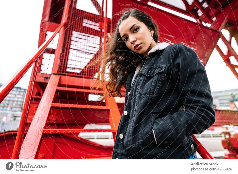 Woman in trendy jeans and jacket on metal stairs woman outfit denim relax step female hipster modern confident casual contemporary millennial calm cool lady