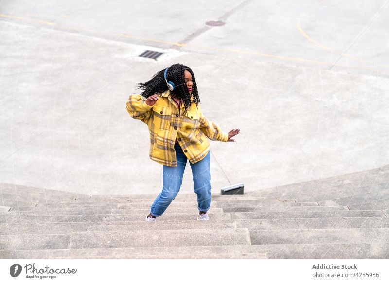 Excited black woman having fun in park headphones enjoy dancing happy excited posture carefree music satisfied delight expressive female cheerful millennial