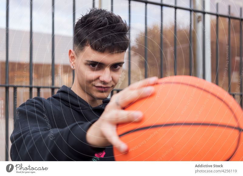 Male teen holding basketball on ground man skill practice hobby game sport activity male training player street leisure young fence focus concentrate action