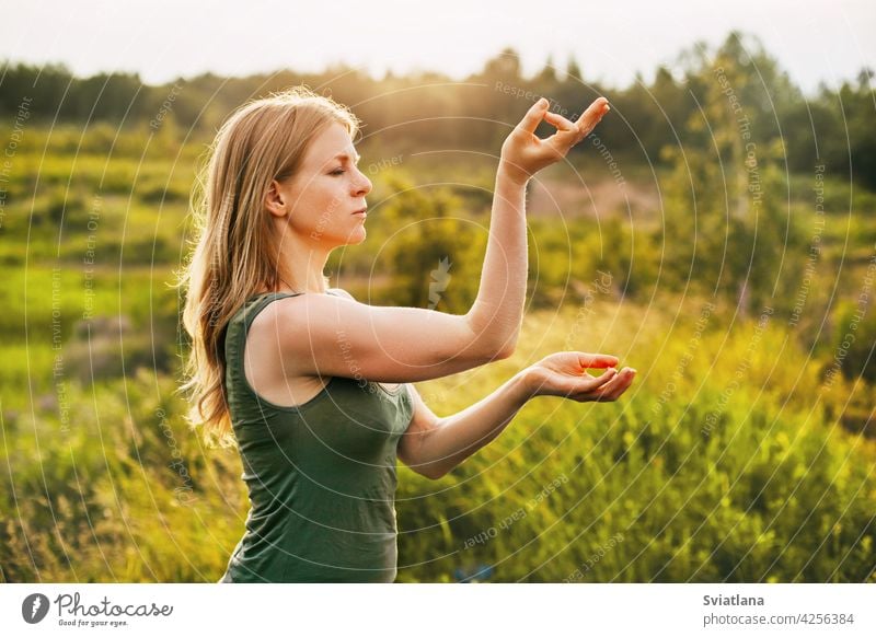 Beautiful blonde does yoga in the fresh air. The concept of mental health and healthy lifestyle young woman asana outdoors nature relax girl female summer