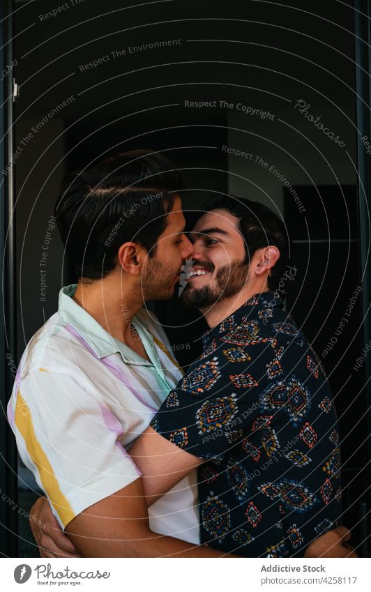Content ethnic gays in moment of kiss at home couple relationship love cheerful pleasure same sex portrait smile spend time romantic amour hug bonding affection