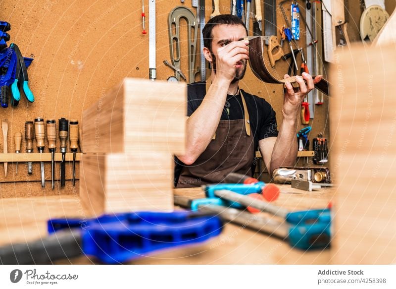 Artisan checking up wooden piece in workroom artisan check up woodwork precise accuracy lumber man workshop small business instrument luthier craftsmanship