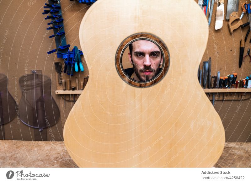 Crop artisan behind guitar sound board in workroom instrument musical classical hole man small business workshop luthier piece woodwork profession craftsman