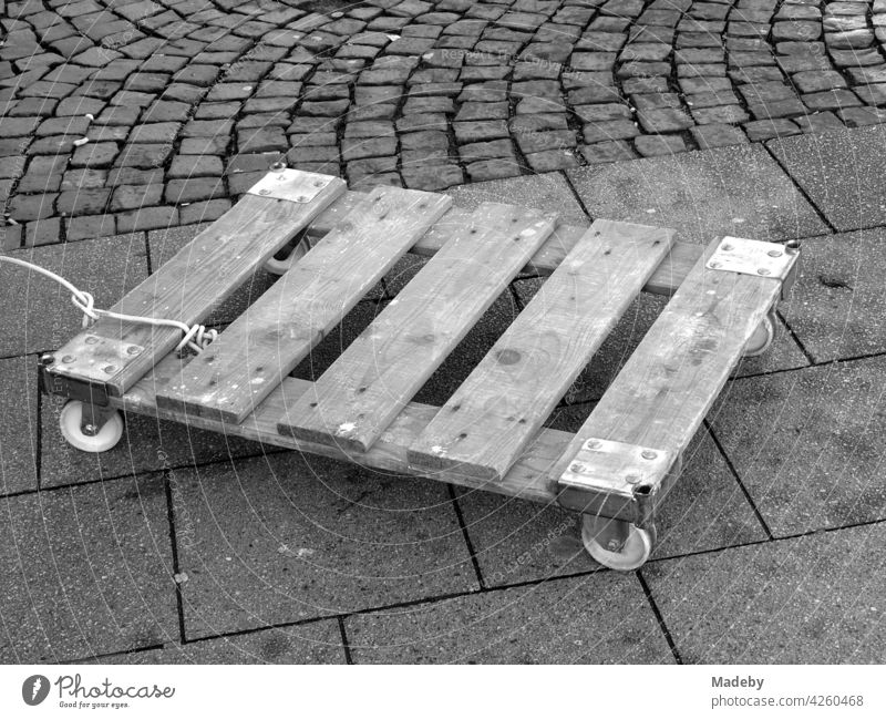 Lined wooden pallet with wheels for transporting boxes at the weekly market at the Bockenheimer Warte in Frankfurt am Main in Hesse, photographed in neo-realistic black and white