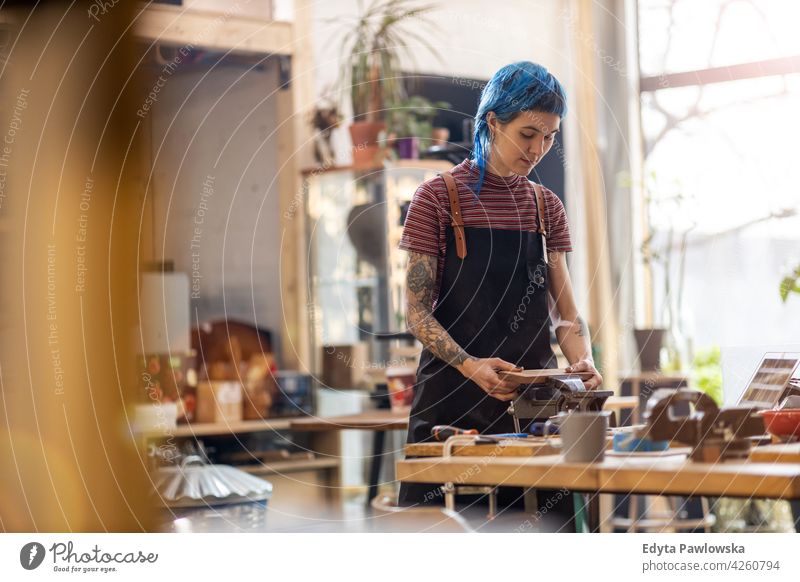 Female Carpenter In Her Workshop diy hipster hair tattoos woman female owner profession service workshop small business employee working workplace maintenance