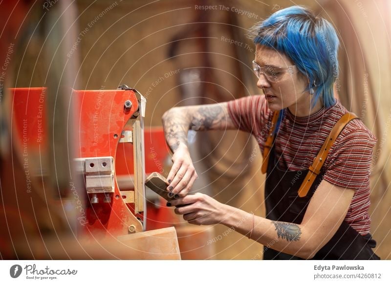 Young craftswoman during her work diy hipster hair tattoos female owner profession service workshop small business employee working workplace maintenance adult