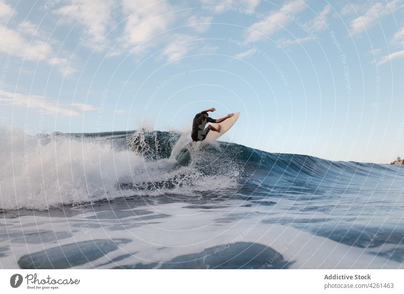 Unrecognizable athlete practicing surfing on ocean wave surfer practice sport extreme energy sea man dynamic flow fast activity brave talent skill cloudy sky