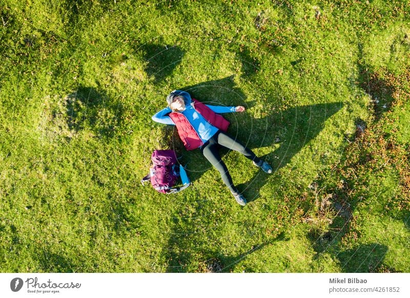 Aerial view of a young woman hiker with a backpack lying on his back on a meadow. lifestyles aerial vacations excursion Spain travels tourism wanderlust people