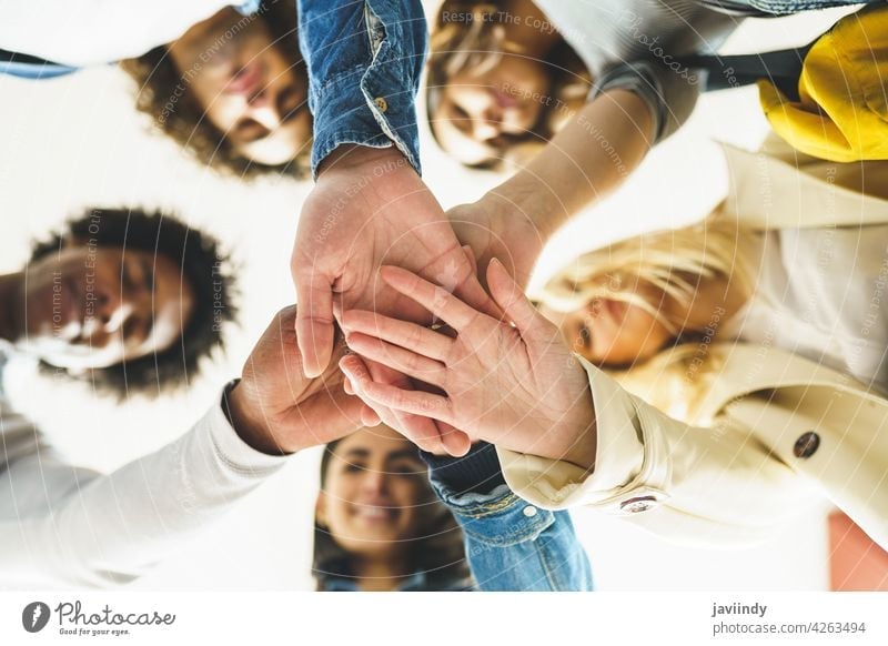 Hands of a multi-ethnic group of friends joined together as a sign of support and teamwork. hand people woman friendship students young partnership youth