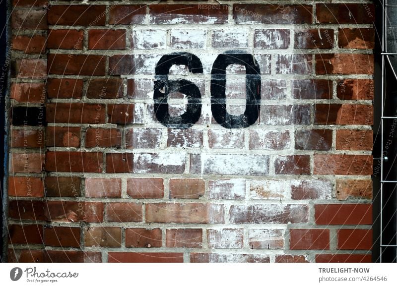 The number 60 (sixty) was painted in large black numerals on a carelessly whitewashed square on the reddish brown brick wall of an old building, perhaps representing a house number
