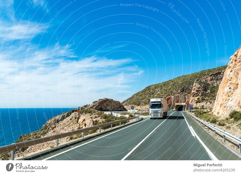 Truck with refrigerated semi-trailer driving along a road by the sea. Refrigerated Beach truck transport Exterior shot Landscape Coast Mediterranean perishable