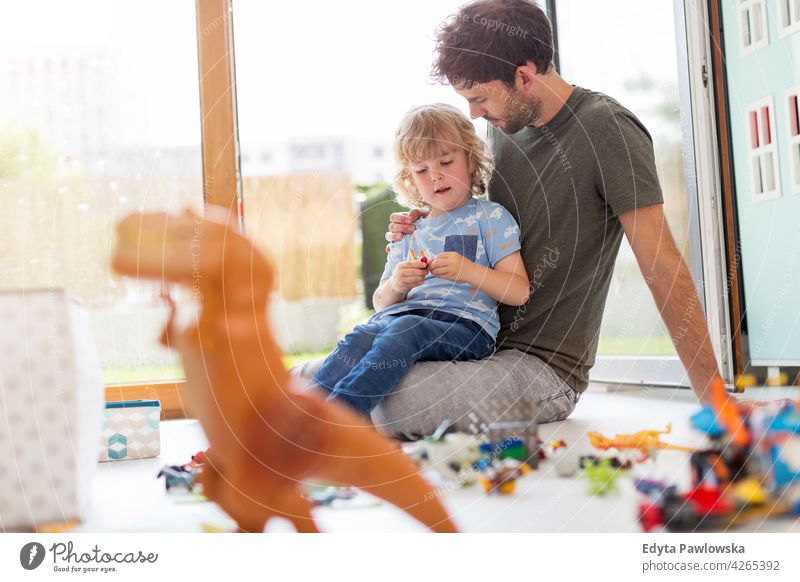Father playing with his little son at home toys block floor children's room man dad father family parents relatives boy kids relationship together togetherness