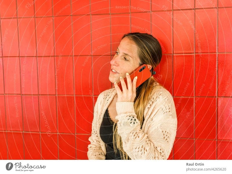 Woman talking on cell phone on red background.Female using phone, making a call, technology lifestyle. person woman smartphone cellphone concept outdoor use