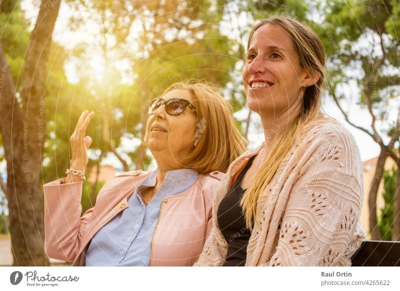 Happy family having fun on weekend.Elderly mother and her adult daughter talking and enjoy time together in nature park at sunset. women happy young woman old