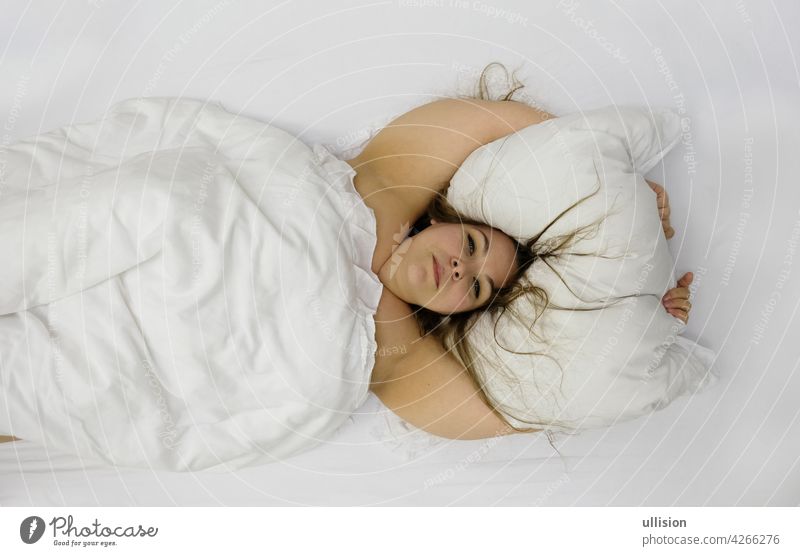 Portrait of a confident positive cheerful plump woman in bed hugging pillow. Cute plus size girl relaxing in bedroom, copy space overcoming weight laziness