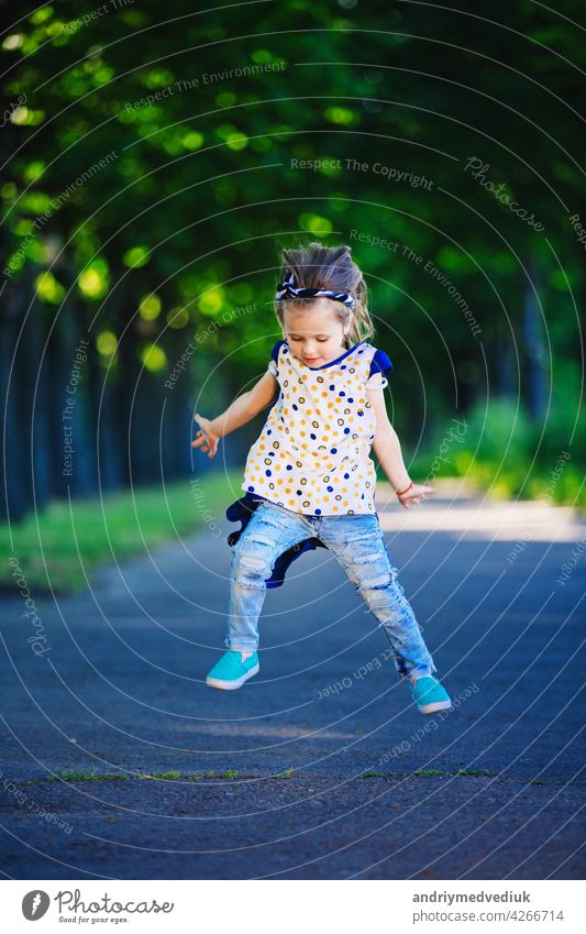 Cute little girl is having fun, jumping and laughing outdoors. happy childhood cute kid cheerful young lifestyle people person happiness park grass adorable