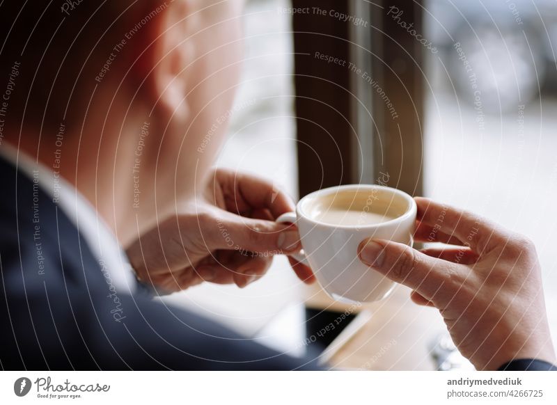 A man in a business suit holds a cup of hot coffee in his hands. Morning businessman in cafe .Copy space. drink break male breakfast caffeine table people tea