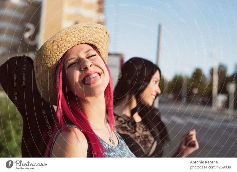 pink haired woman in hat sticking out tongue at camera young attractive 20s joy people person youth urban women pretty pretty people outdoors city walking