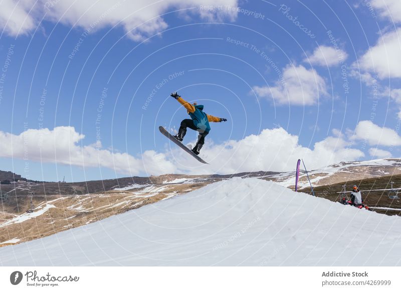 Unrecognizable sportsman riding snowboard in winter mountains ride jump practice energy activity cableway cabin balance nature mask cold weather snowboarding