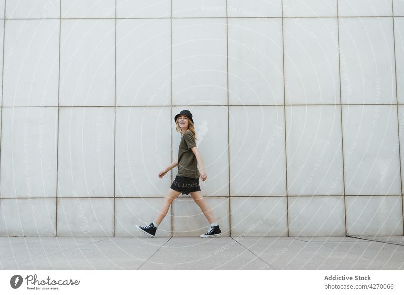 Happy woman walking over urban pavement against wall happy active having fun energy dynamic lifestyle city tile cheerful gumshoe modern stroll carefree street
