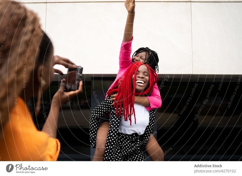 Black woman taking photo of friends having piggyback ride women take photo photo camera having fun laugh enjoy cheerful together female girlfriend friendship