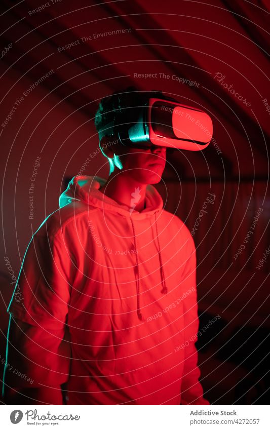 Serious guy in VR glasses in neon room man vr modern headset studio serious virtual reality red male light goggles device gadget experience contemporary
