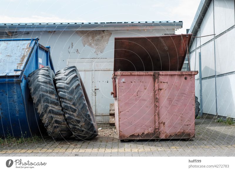 Still life of two scrap metal containers with large tractor tires on a workshop yard tractor tyre Container Workshop yard waste Recycling container recycle