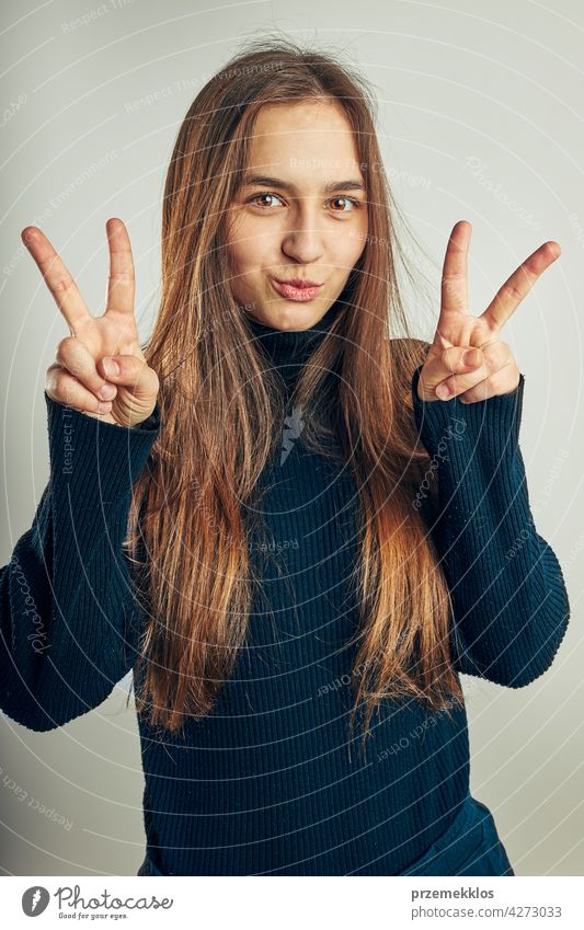 Excited girl gesturing peace sign. Portrait in positive mood. Girl making victory sign gesture portrait headshot woman model person female young teenager pretty