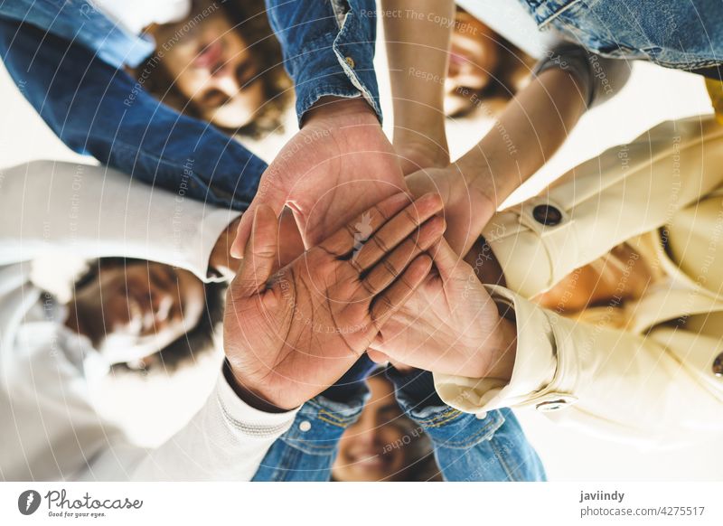 Hands of a multi-ethnic group of friends joined together as a sign of support and teamwork. hand people woman friendship students young partnership youth