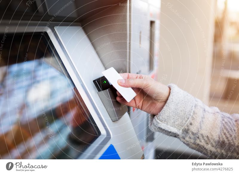 Woman purchasing fare for public transit holding technology using wireless senior seniors pensioner pensioners woman casual outdoors one person retiree retired