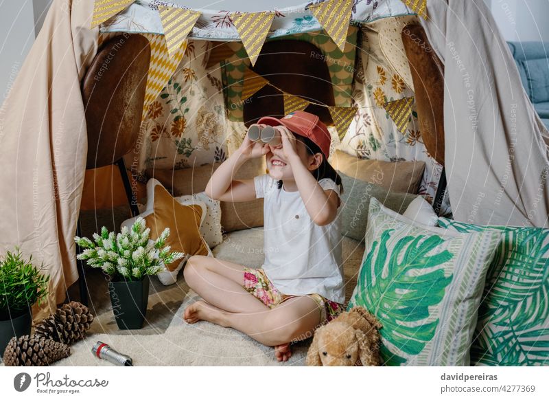 Girl playing with cardboard binoculars while camping at home happy girl observing vacation diy tent smiling carton toilet paper tubes holding toys female little