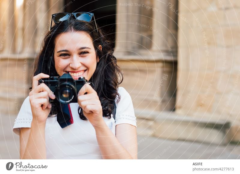 Happy tourist woman taking pictures of the old town with a retro camera young happy smile toothy photo photography summer girl people lifestyle travel monument