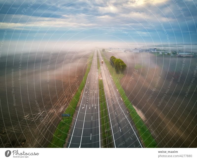 Aerial view of a highway covered by fog. Early misty morning. Road in rainy spring summer fields. road cloud weather overcast transport rural sky scene roadway