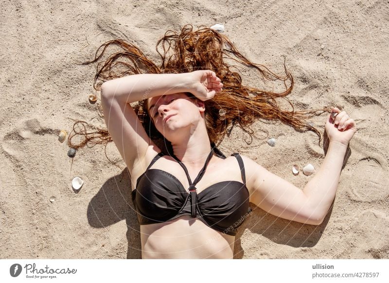 beautiful young woman in black bikini laying in the sunshine on