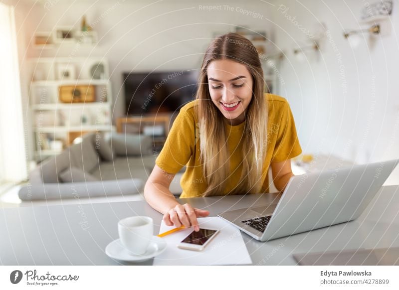 Young woman using her laptop at home computer internet online technology notebook communication wireless people young adult casual attractive female smiling