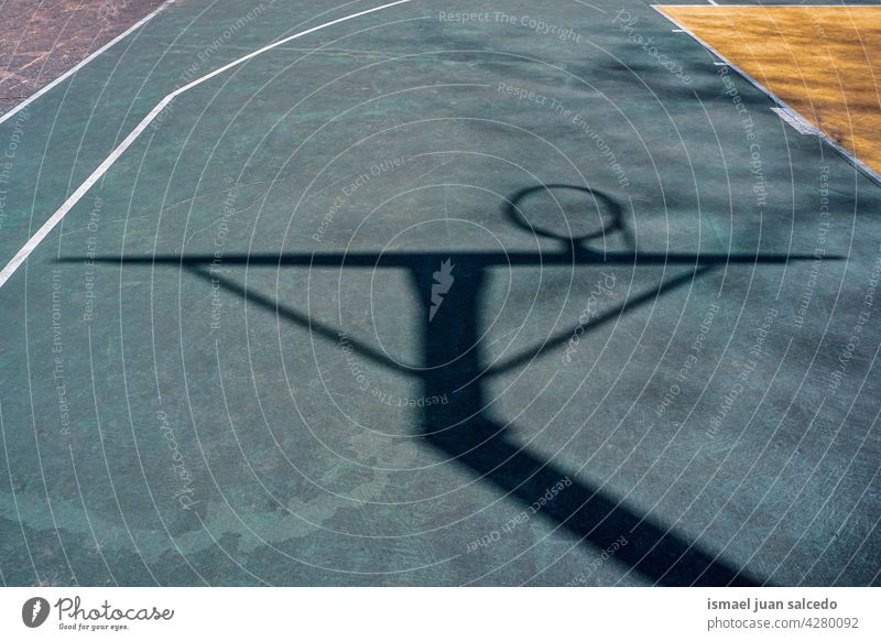 street basketball hoop shadows on the ground silhouette sunlight court field floor sport equipment game competition play playing abandoned park playground