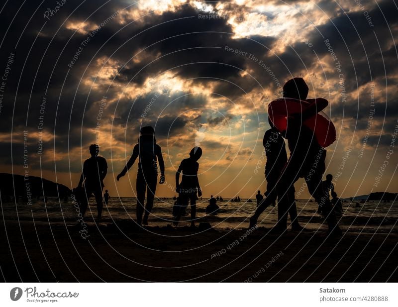 Silhouettes of people playing in the sea at a public beach silhouette landscape sky sand evening vacation sun sunset together summer young ocean water nature