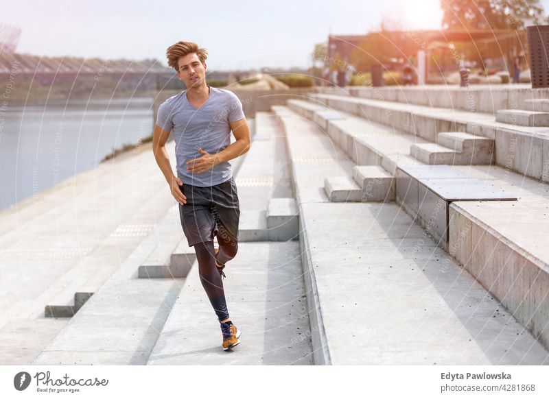 Young man running in urban area Jogger runner jogging people young male energy exercise clothing exercising fitness recreation sport healthy lifestyle action
